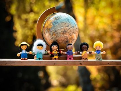 Eine Gruppe von Figuren, die Menschen verschiedener Nationalitäten repräsentieren vor einer Weltkugel.