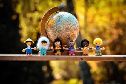 Eine Gruppe von Figuren, die Menschen verschiedener Nationalitäten repräsentieren vor einer Weltkugel.