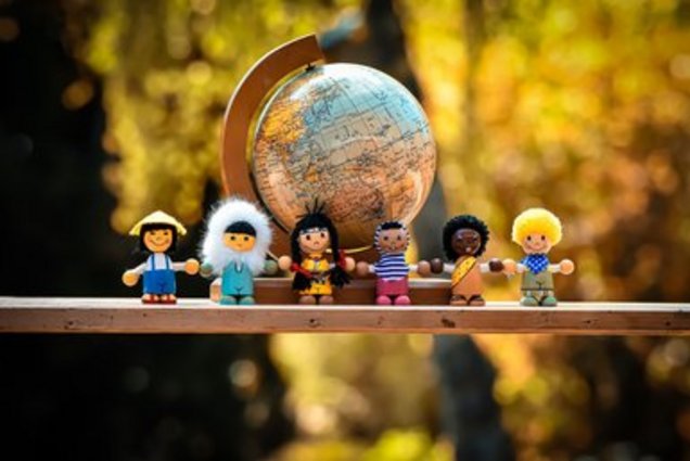 Eine Gruppe von Figuren, die Menschen verschiedener Nationalitäten repräsentieren vor einer Weltkugel.