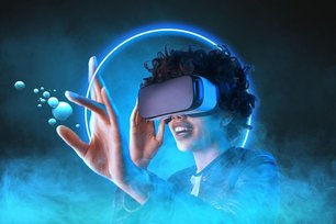 Eine Person trägt eine VR Brille und greift einen virtuellen Gegenstand mit den Fingern.